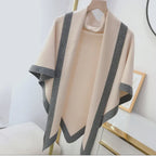 Beige shawl with gray trim on a mannequin against a white background