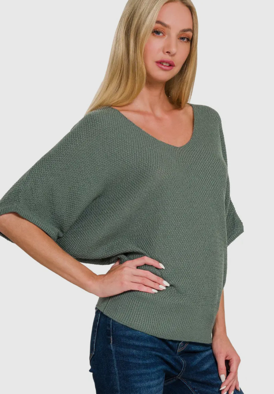 Woman wearing a green sweater and blue jeans on a white background