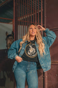 Woman in denim jacket and jeans wearing Rodeo High Club shirt, horse stable, spokane cheney boutique